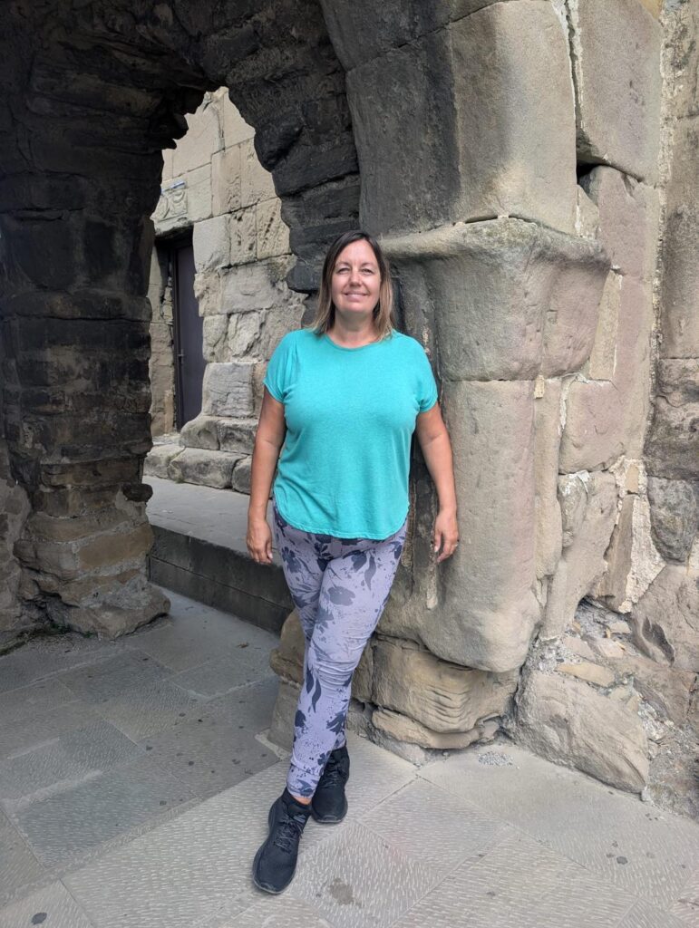 Business growth coach. Gil Devlin standing beneath a historic stone archway in Tbilisi, Georgia, during her global travels.