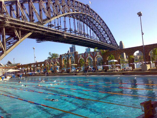 Sydney Harbour Bridge over North Sydney Olympic Pool lanes, symbolizing bridge-building and structured teamwork supported by DISC communication skills training.