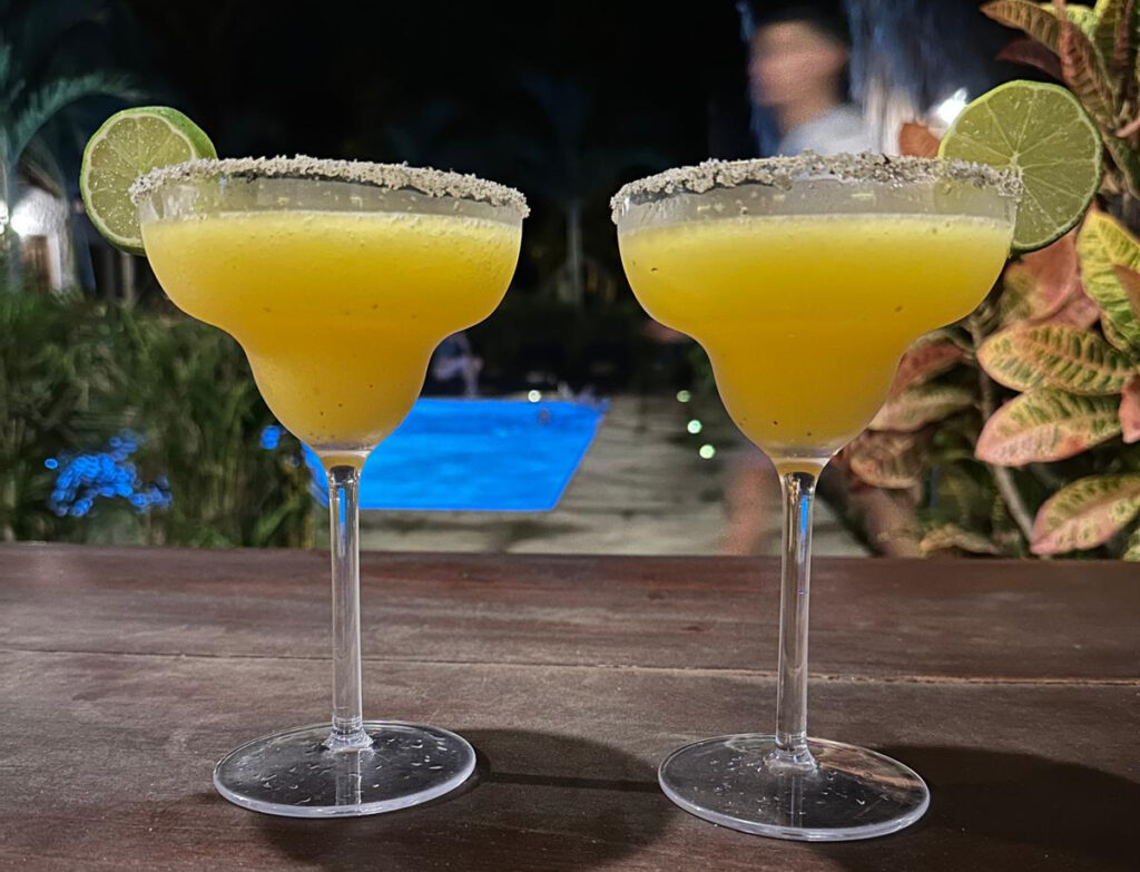 Two lime-garnished cocktails set against a poolside backdrop, reflecting the role of positive thinking in business and enjoying professional success